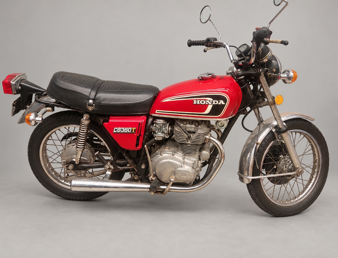 Red 1975 Honda CB360T with black seat, chrome exhaust and spoked wheels